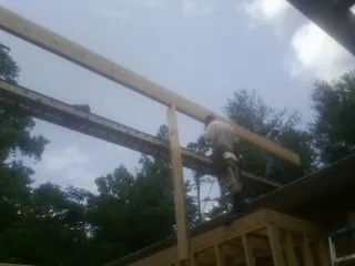 Carpenter setting a ridge beam over a new addition frame — Ice Dam Removal by Roofing Brothers in Delaplane