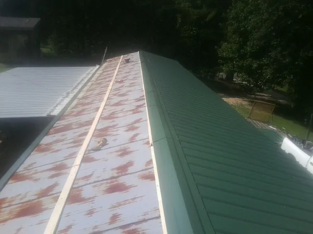 Old rusted panels beside newly installed green metal roofing — Wind Damage Roof Repair by Roofing Brothers in Delaplane
