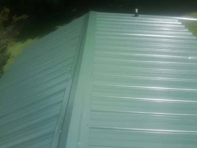 New green metal panels meeting at the ridge of a roof — Flat Roof Repair work by our crew in Delaplane