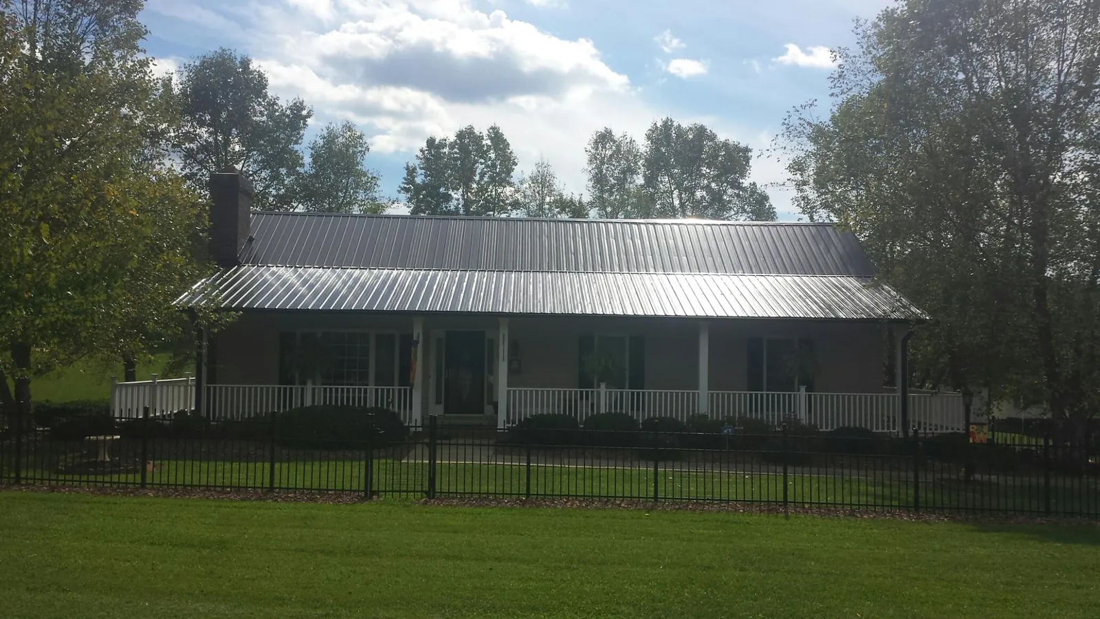 Gray metal roof on a brick ranch with a full width front porch — Gutter Guard Installation work by our crew in Delaplane