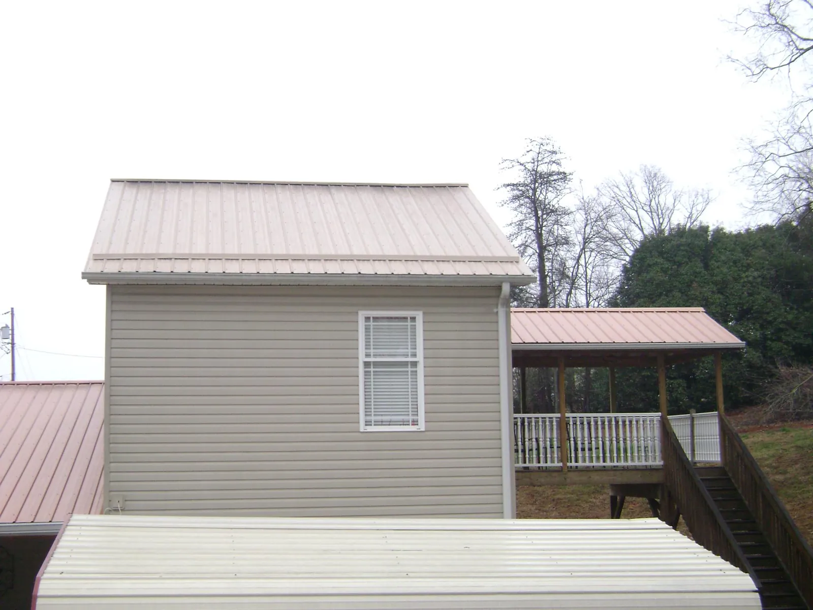 Tan metal roofs on a two story addition and attached porch, from a Roof Replacement job in Delaplane