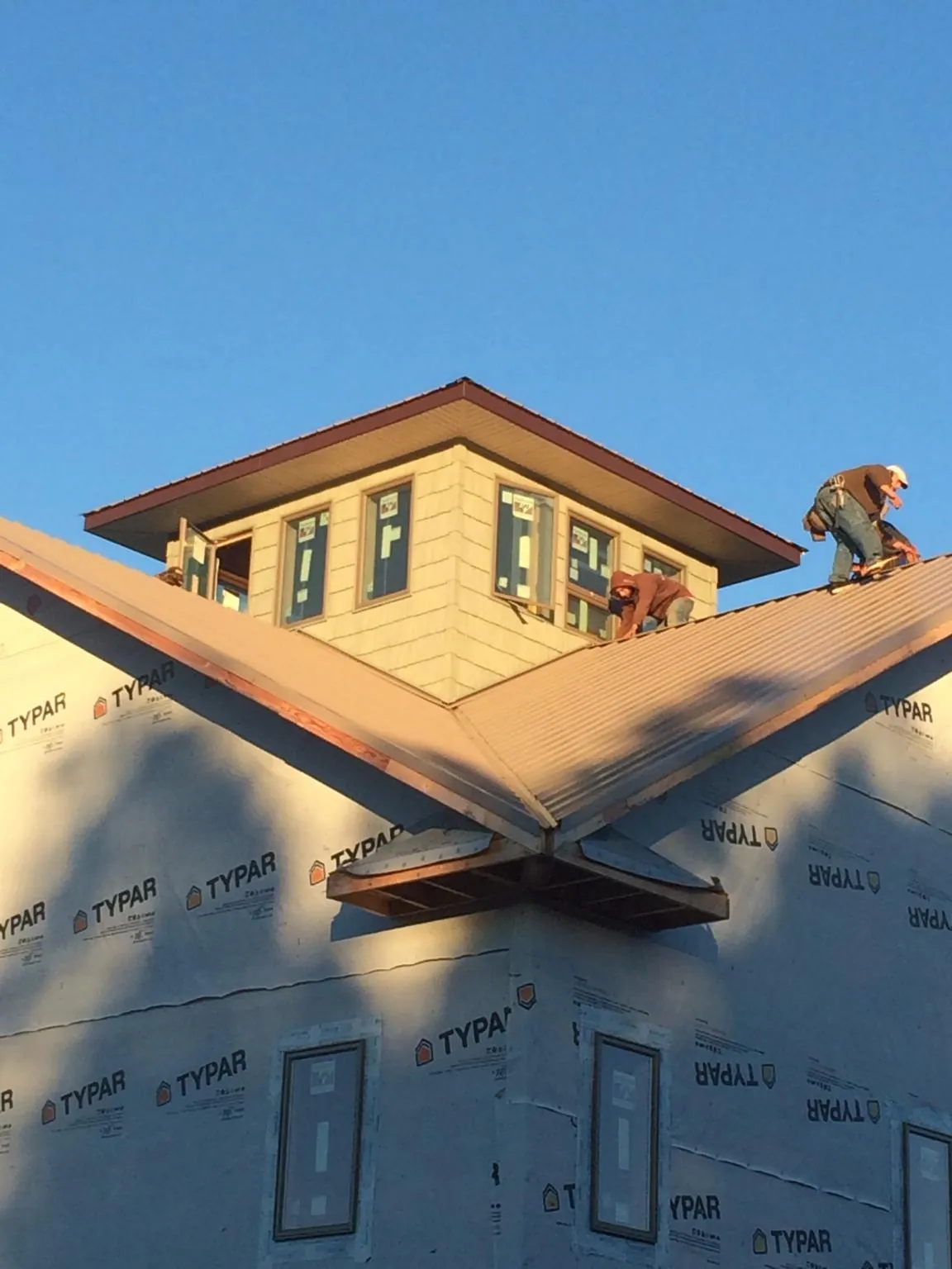 Roofers working around a rooftop cupola on a new metal roof at sunset — Roof Waterproofing in Delaplane by Roofing Brothers